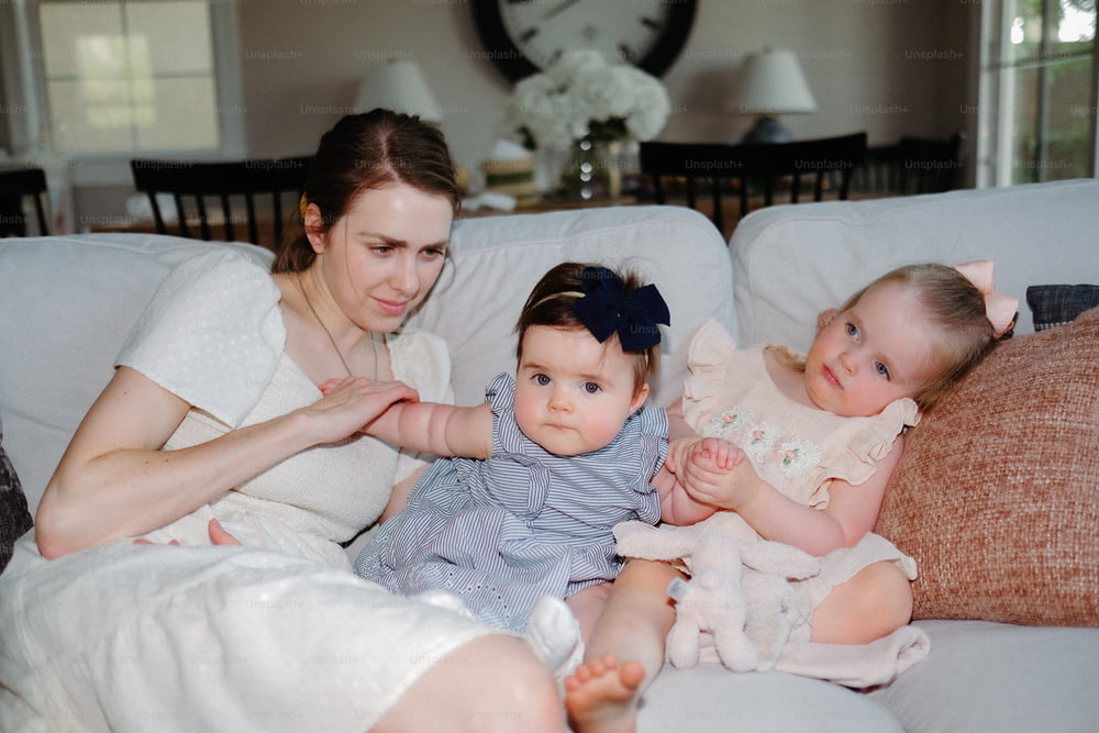 a woman sitting on a couch with two babies