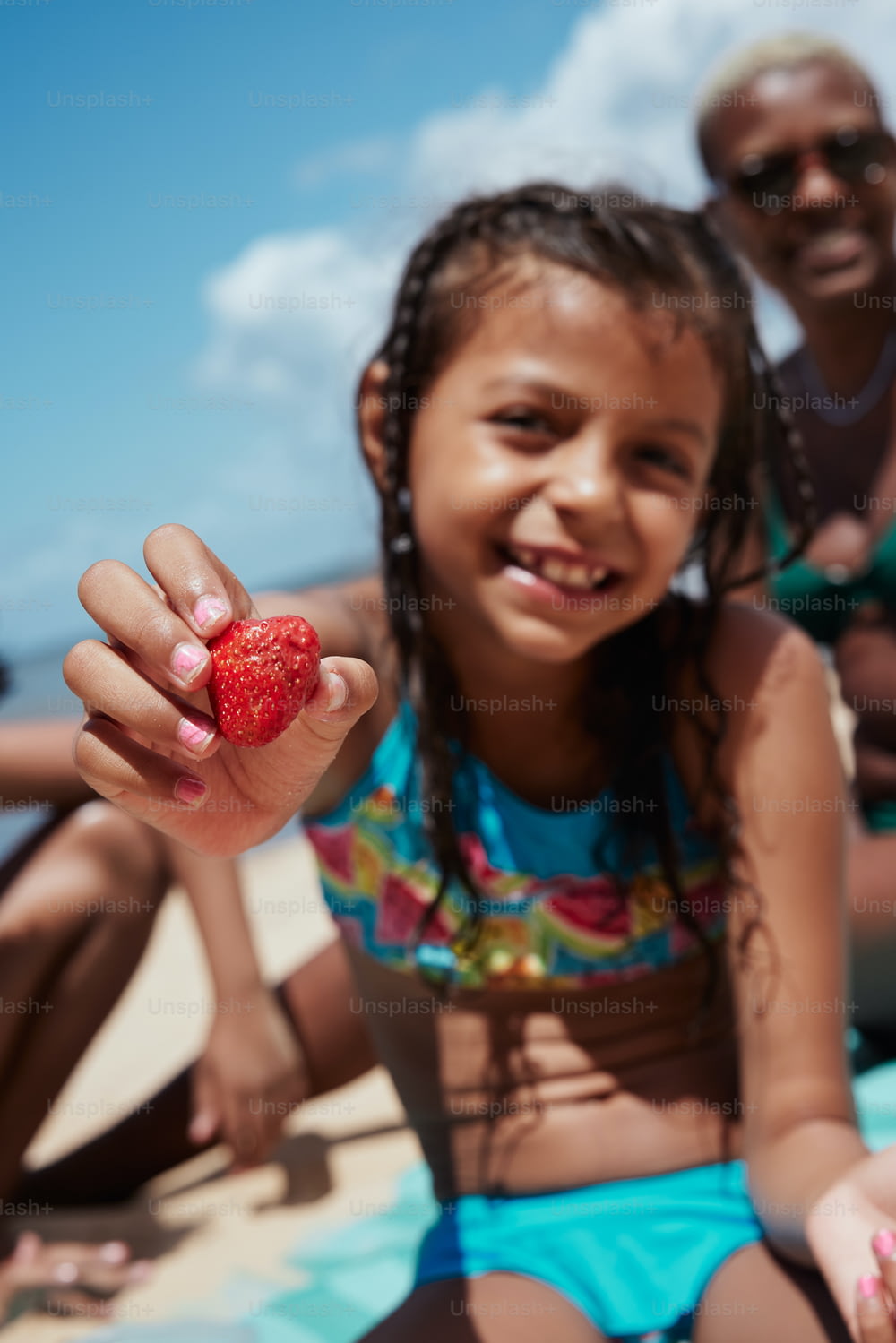 uma garotinha segurando um morango em sua mão