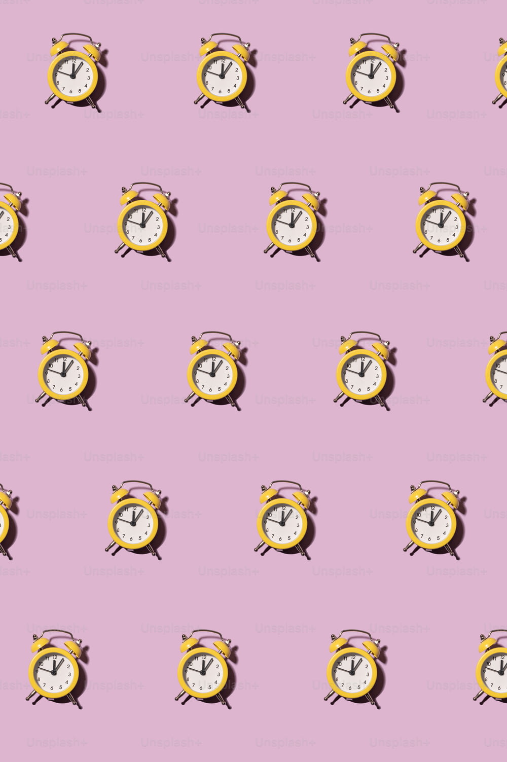 a pink background with a pattern of yellow and white clocks