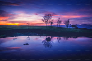 Ein wunderschöner Sonnenuntergang über einem kleinen Teich mitten auf einem Feld
