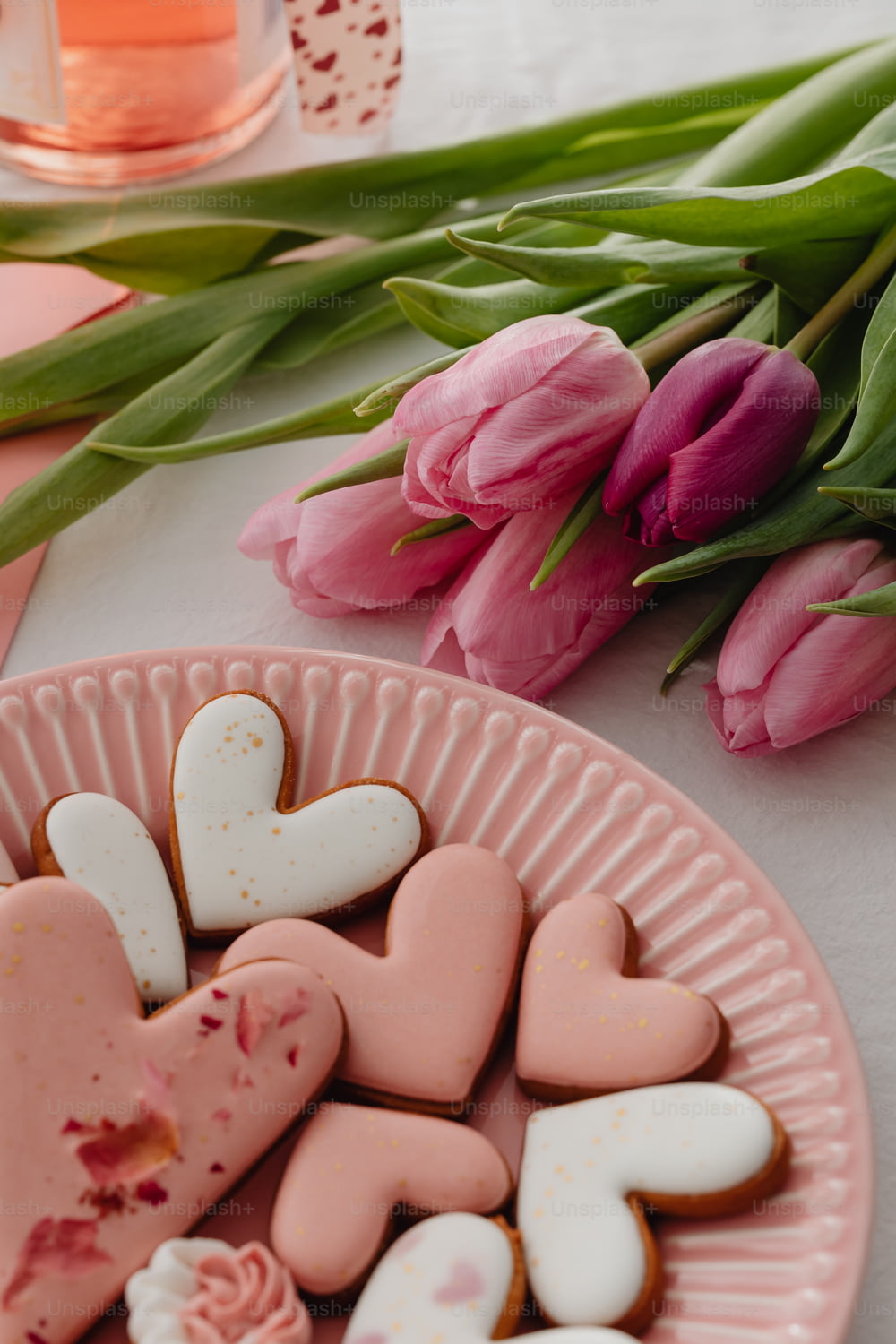 a plate of heart shaped cookies next to pink tulips