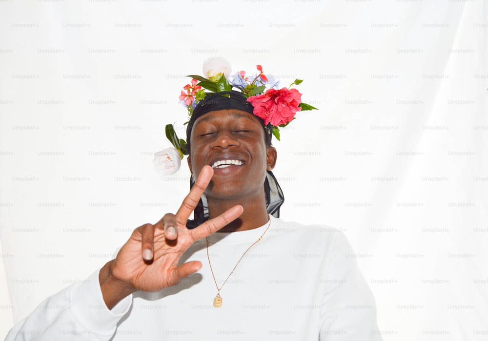 a man with a flower crown on his head making a peace sign