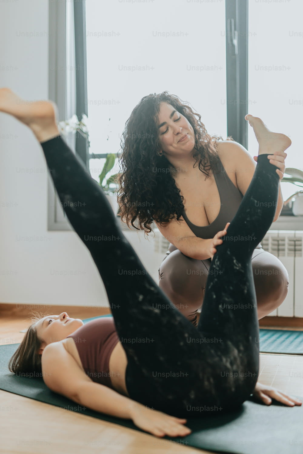 two women doing yoga on a mat in front of a window