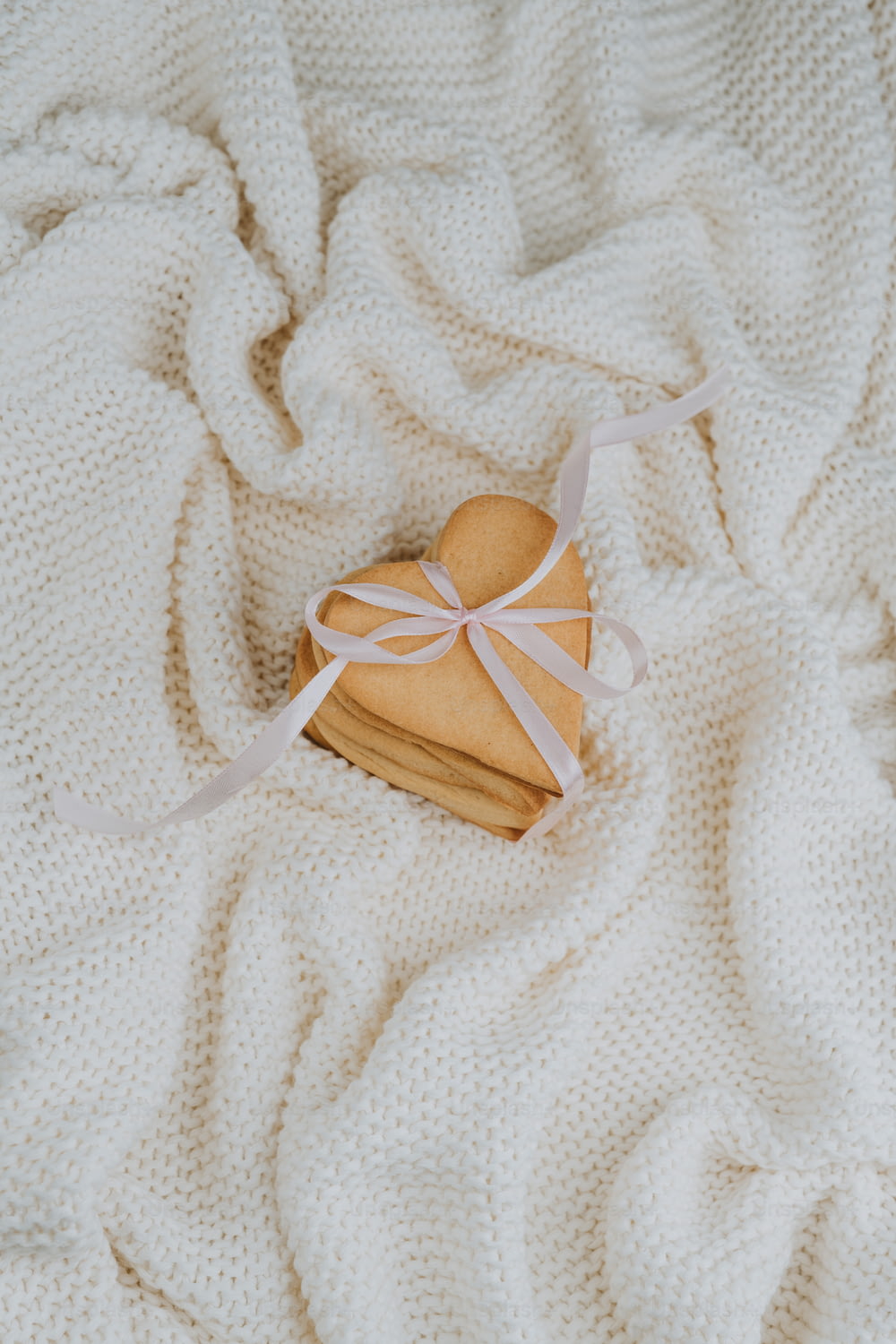 a heart shaped cookie on a white blanket