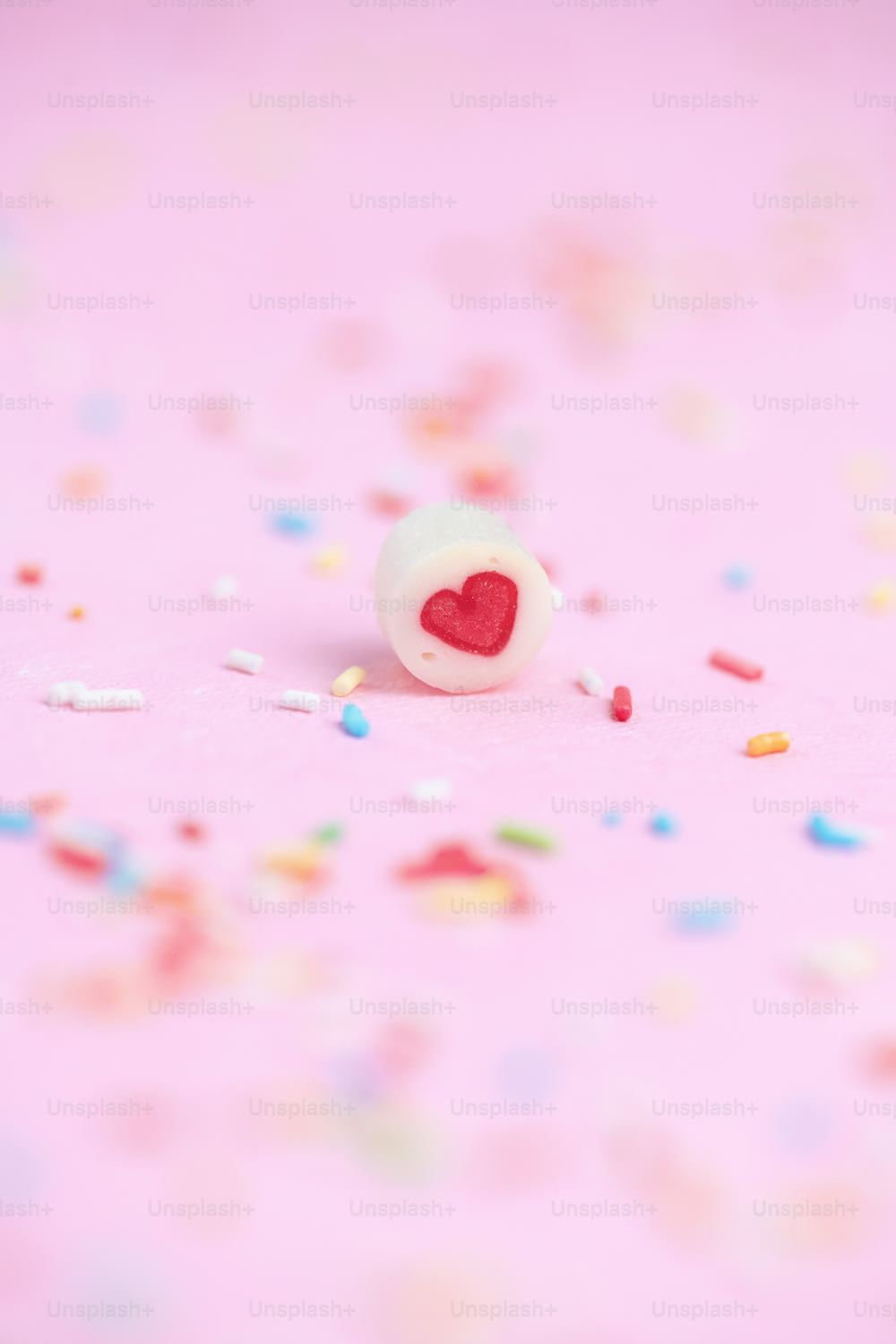 a heart shaped button sitting on top of a pink surface