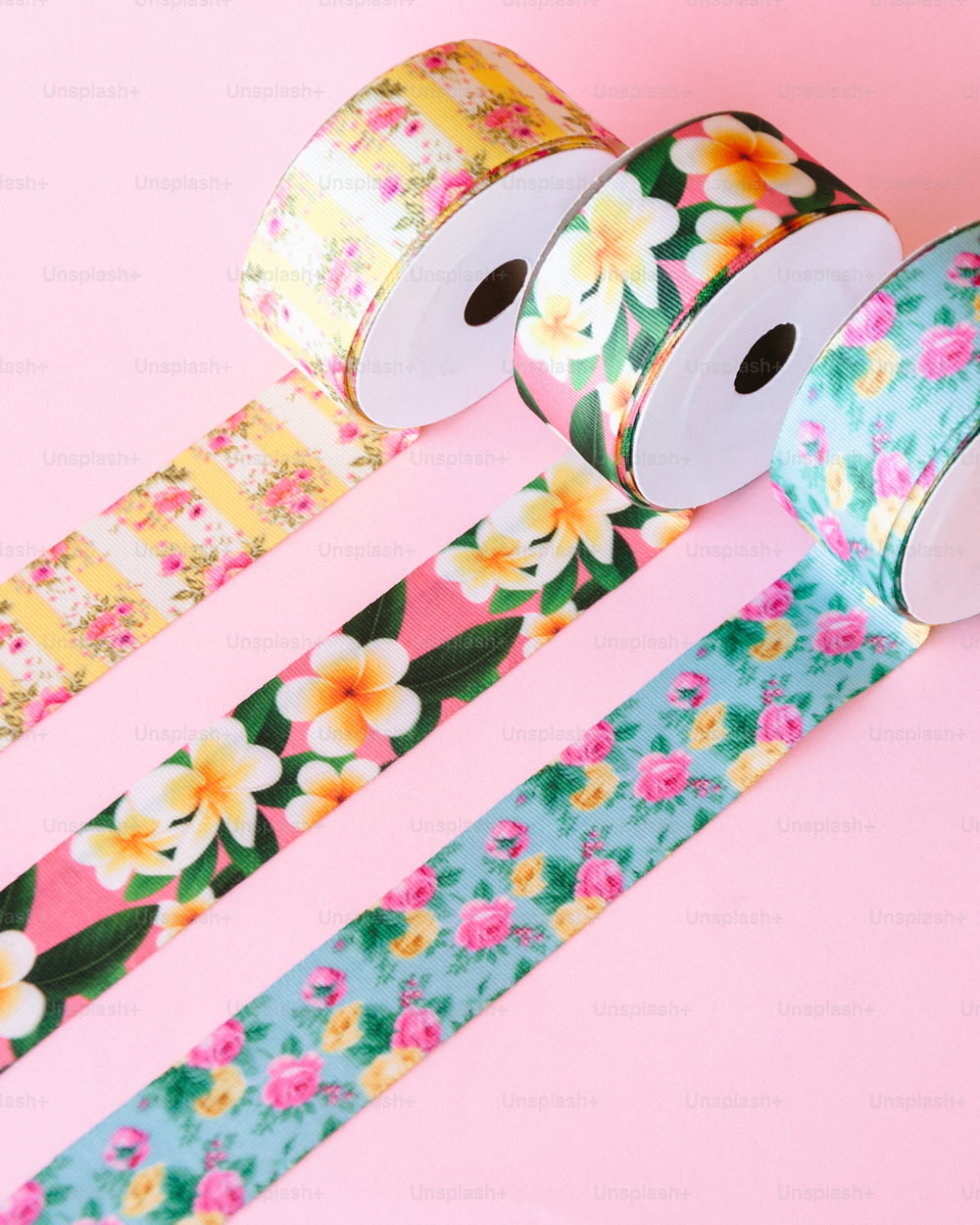 three rolls of floral washi tape on a pink background