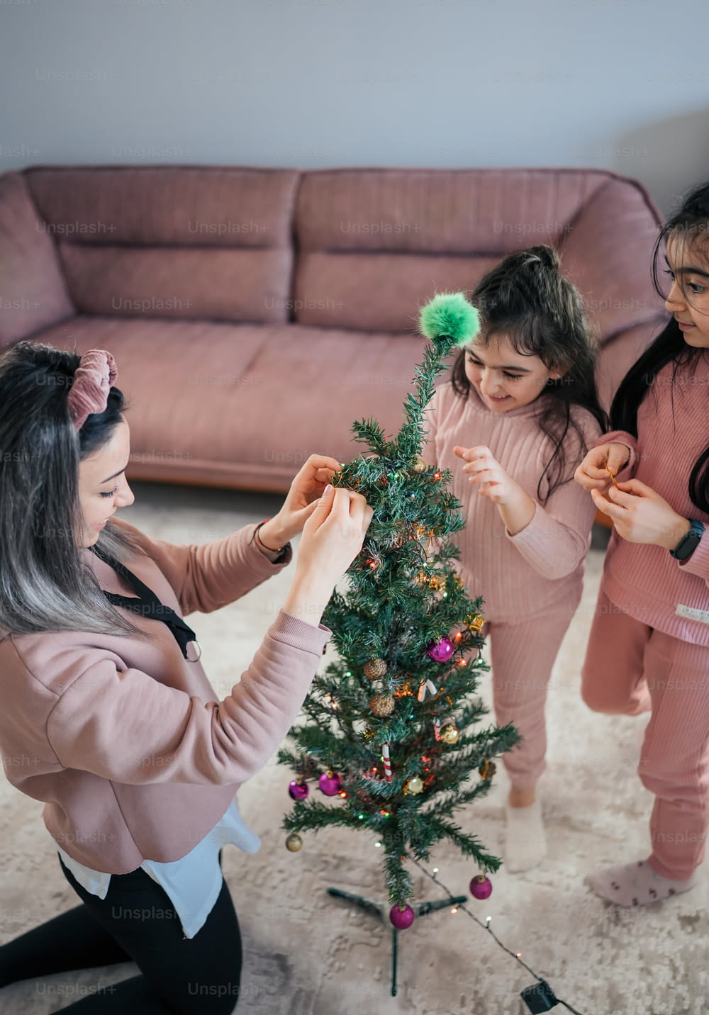 a group of girls decorating a small christmas tree