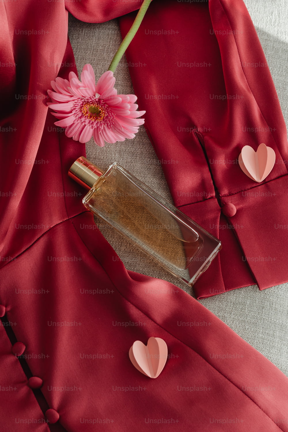 eine Flasche Parfüm neben einer rosa Blume