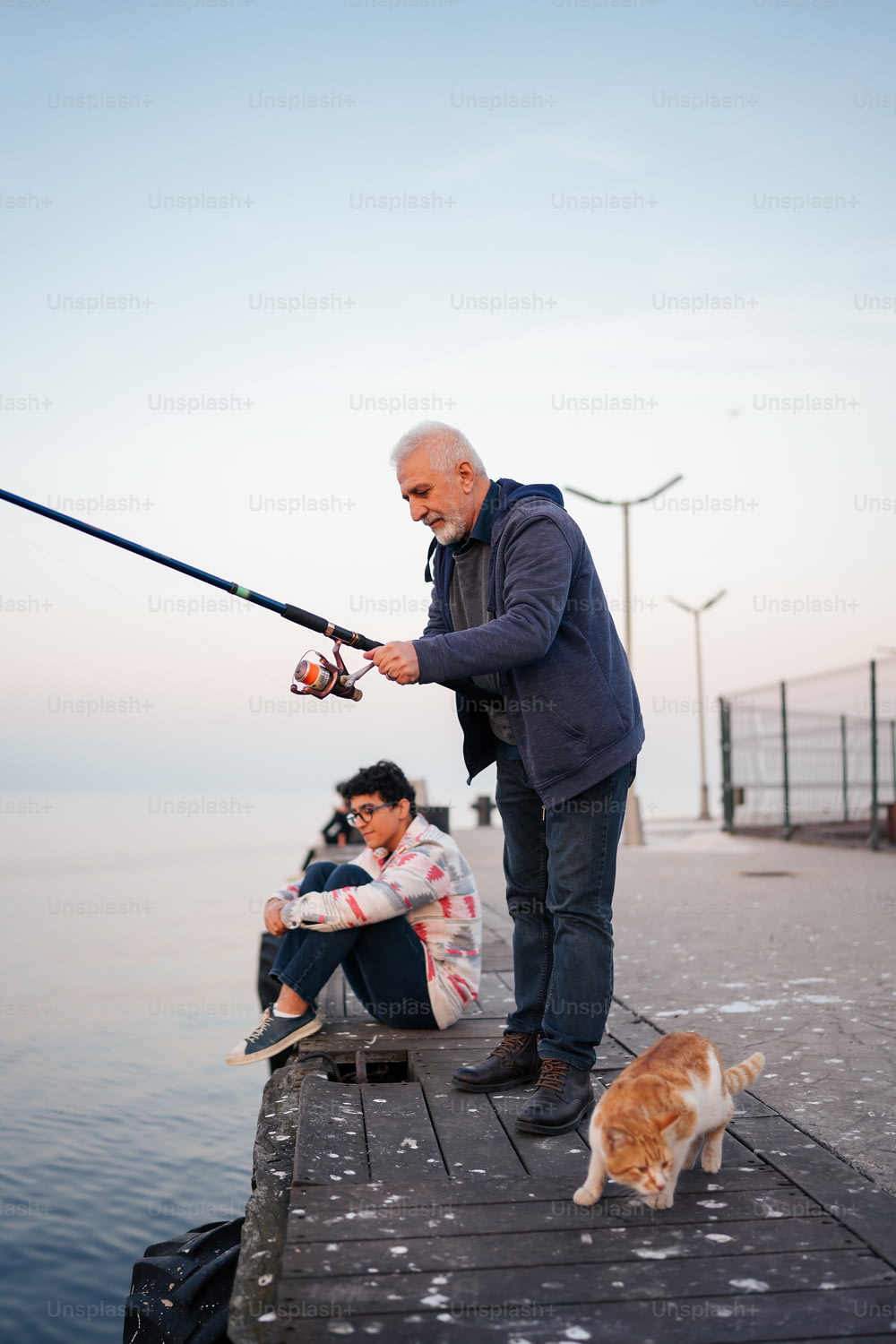 a man and a cat fishing on a pier