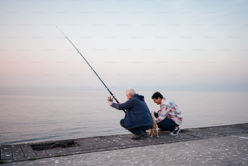un homme agenouillé à côté d’une femme tenant une canne à pêche