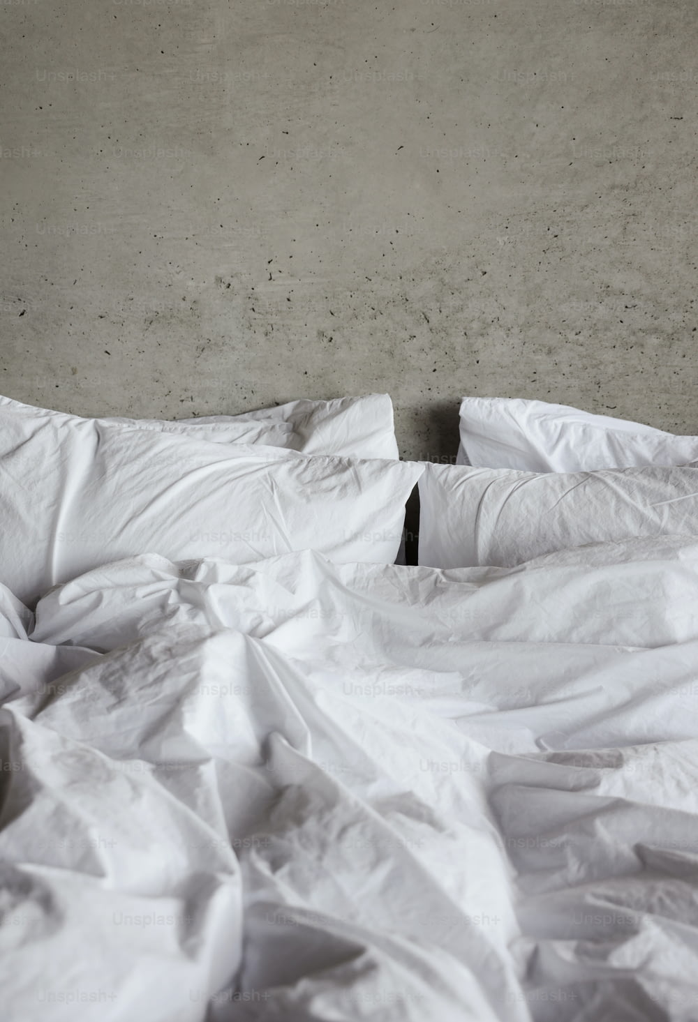 una cama sin hacer con sábanas blancas y almohadas