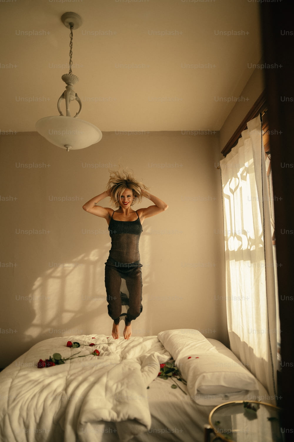 uma mulher que pula em uma cama em um quarto