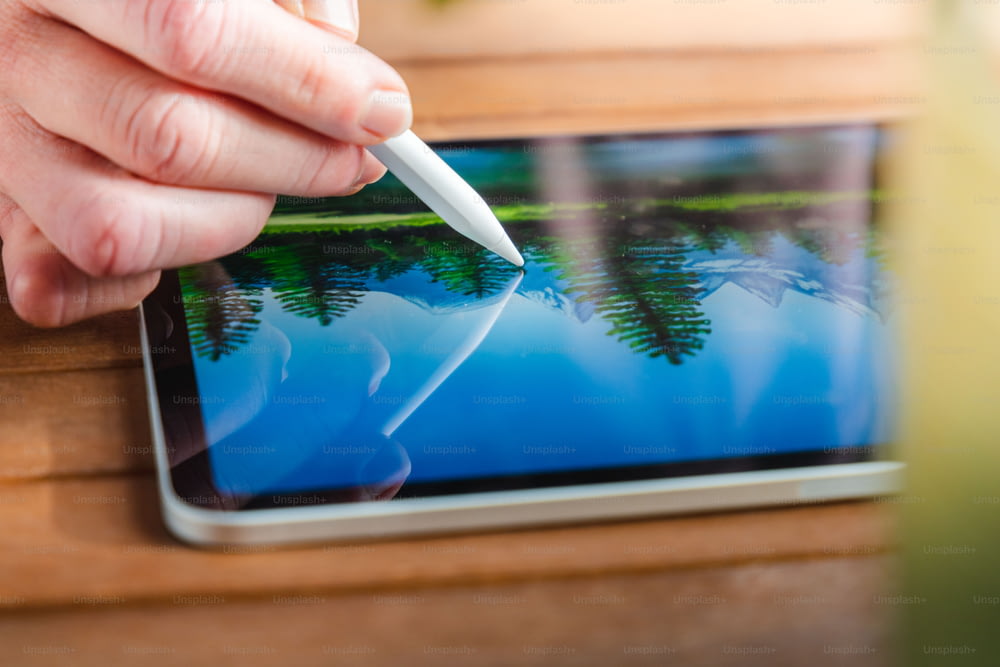 una persona sta tenendo una penna sopra un tablet