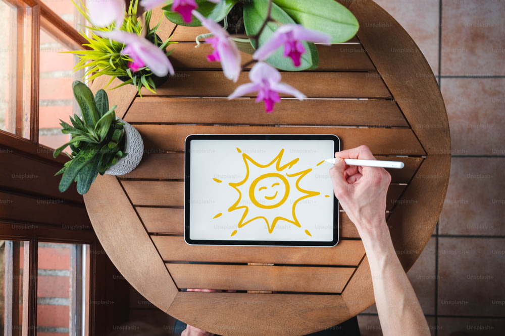 Eine Person, die eine Sonne auf ein Tablet zeichnet