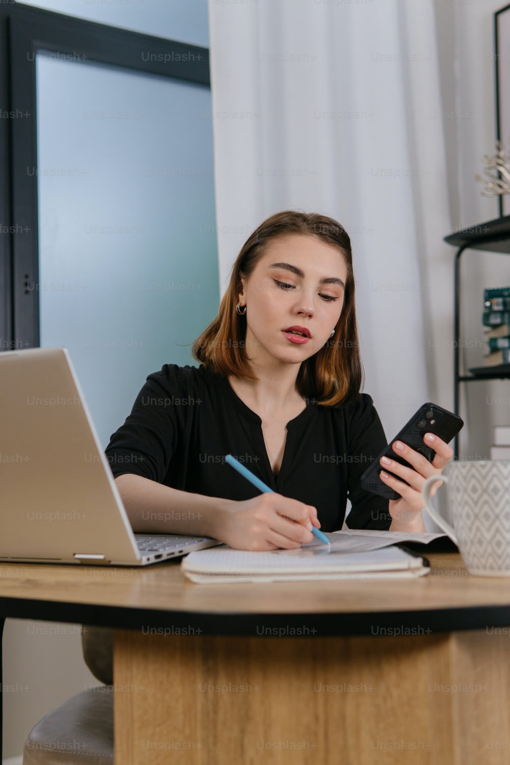 une femme assise à un bureau utilisant un téléphone cellulaire