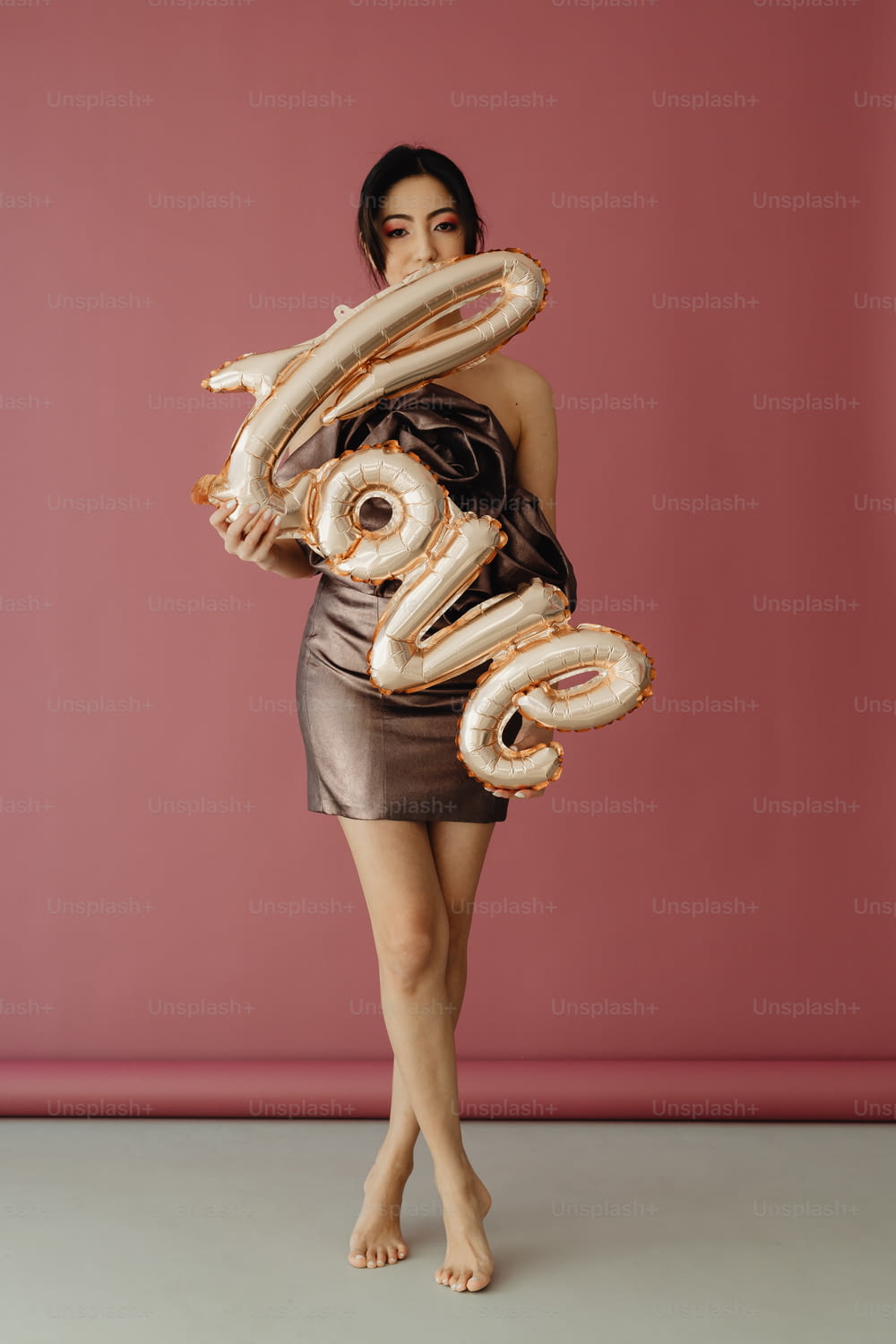 a woman in a short dress holding a large number balloon