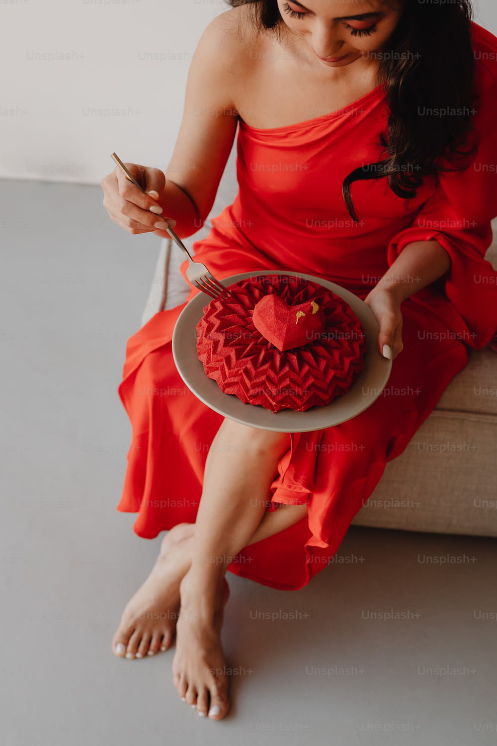 a woman in a red dress holding a heart shaped cake