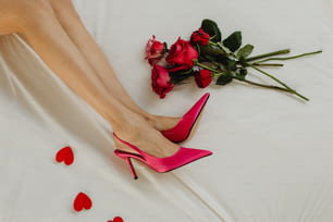 Beine und Fersen einer Frau auf einem Bett mit Rosen