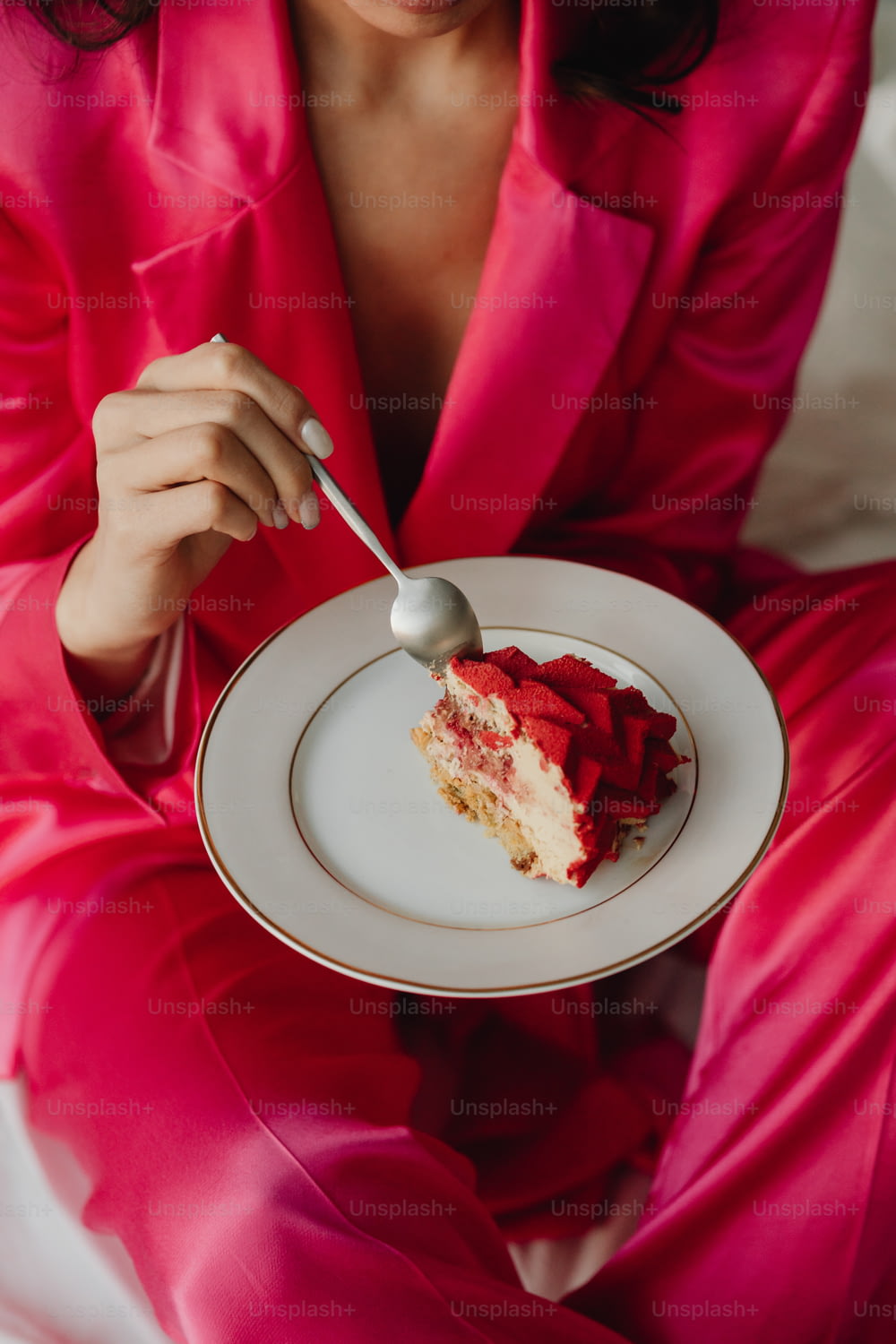 ピンクのスーツを着た女性がケーキが乗った皿を持つ