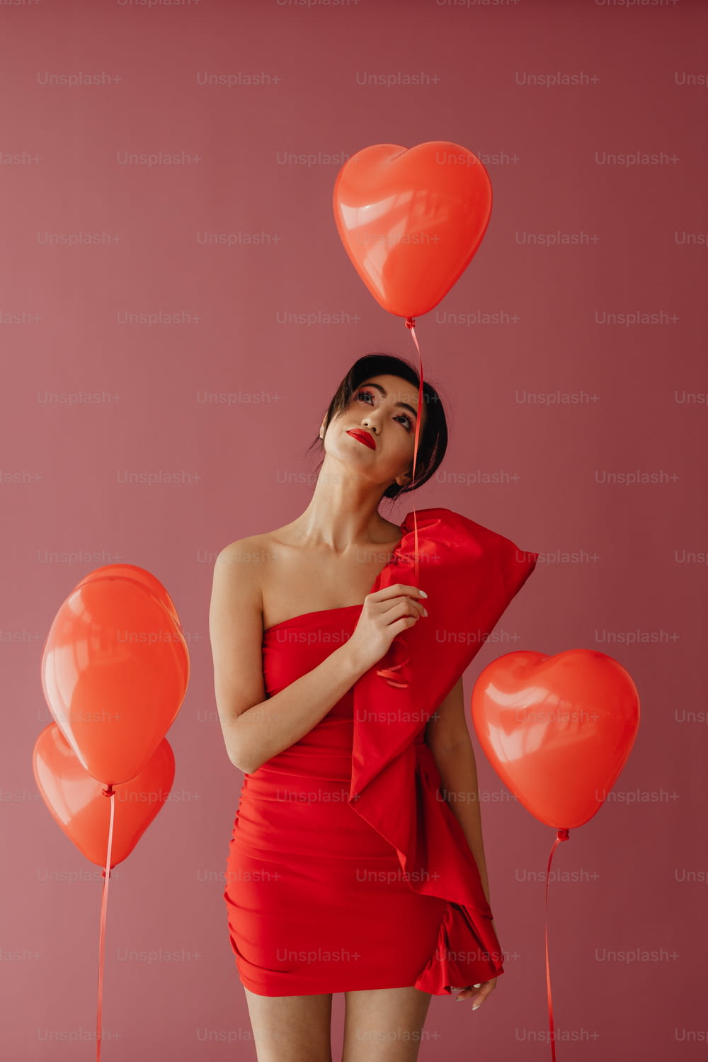 Eine Frau in einem roten Kleid, die einen Haufen Luftballons hält