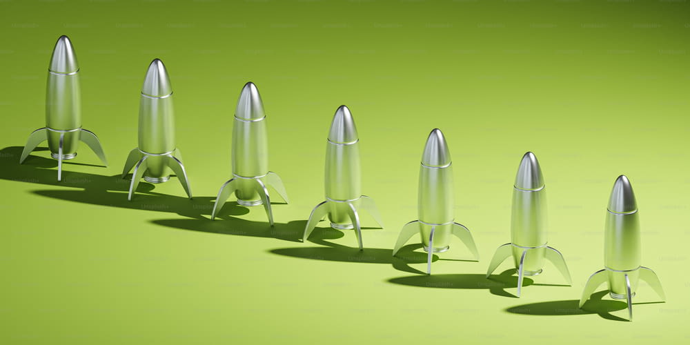 Una fila di razzi metallici seduti sopra una superficie verde