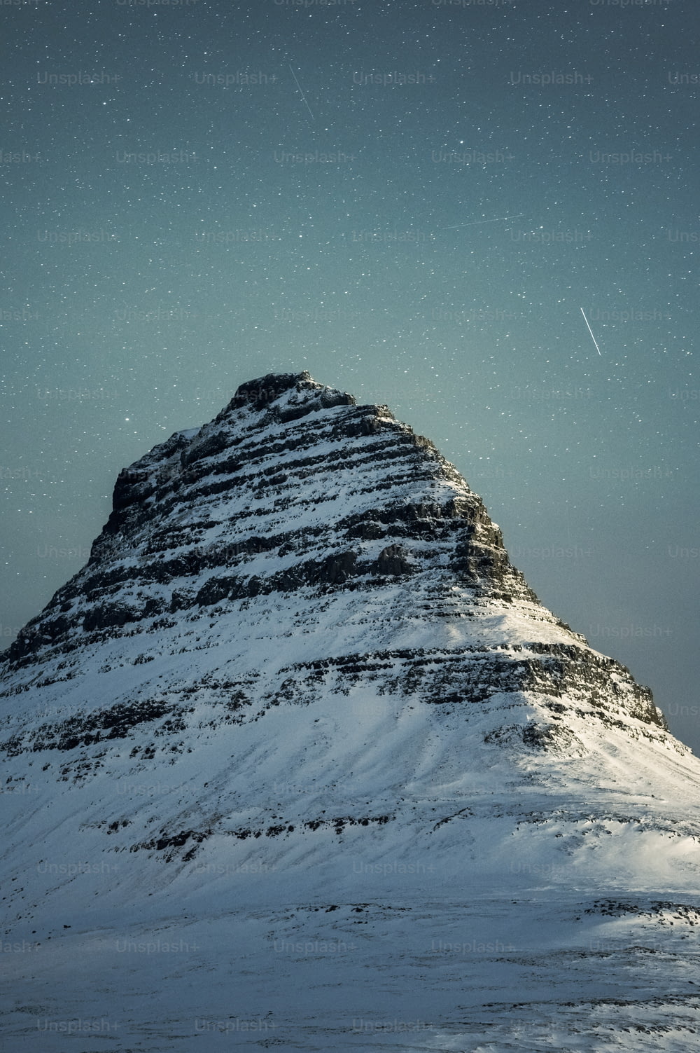 a snow covered mountain under a star filled sky