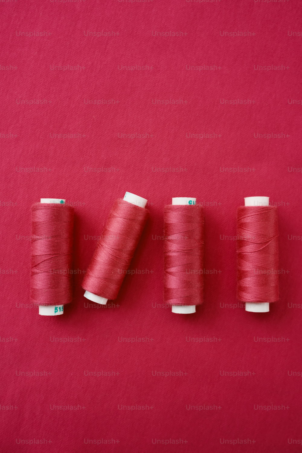 Trois bobines de fil sur fond rouge