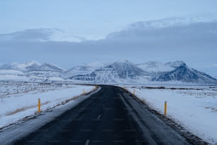 Un camino con nieve en el suelo y montañas al fondo