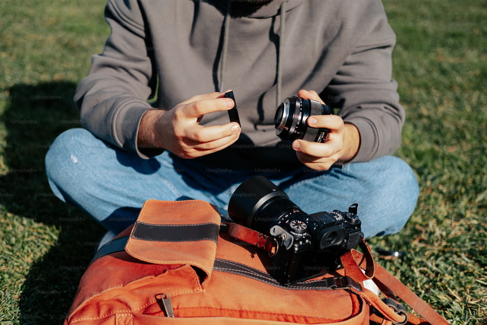 Ein Mann sitzt im Gras und hält eine Kamera in der Hand