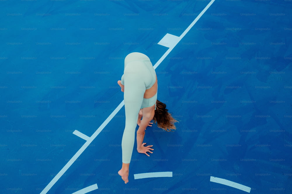 Eine Frau im weißen Outfit ist auf einem blauen Tennisplatz