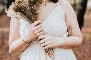 a woman in a white dress holding a bunch of dried flowers