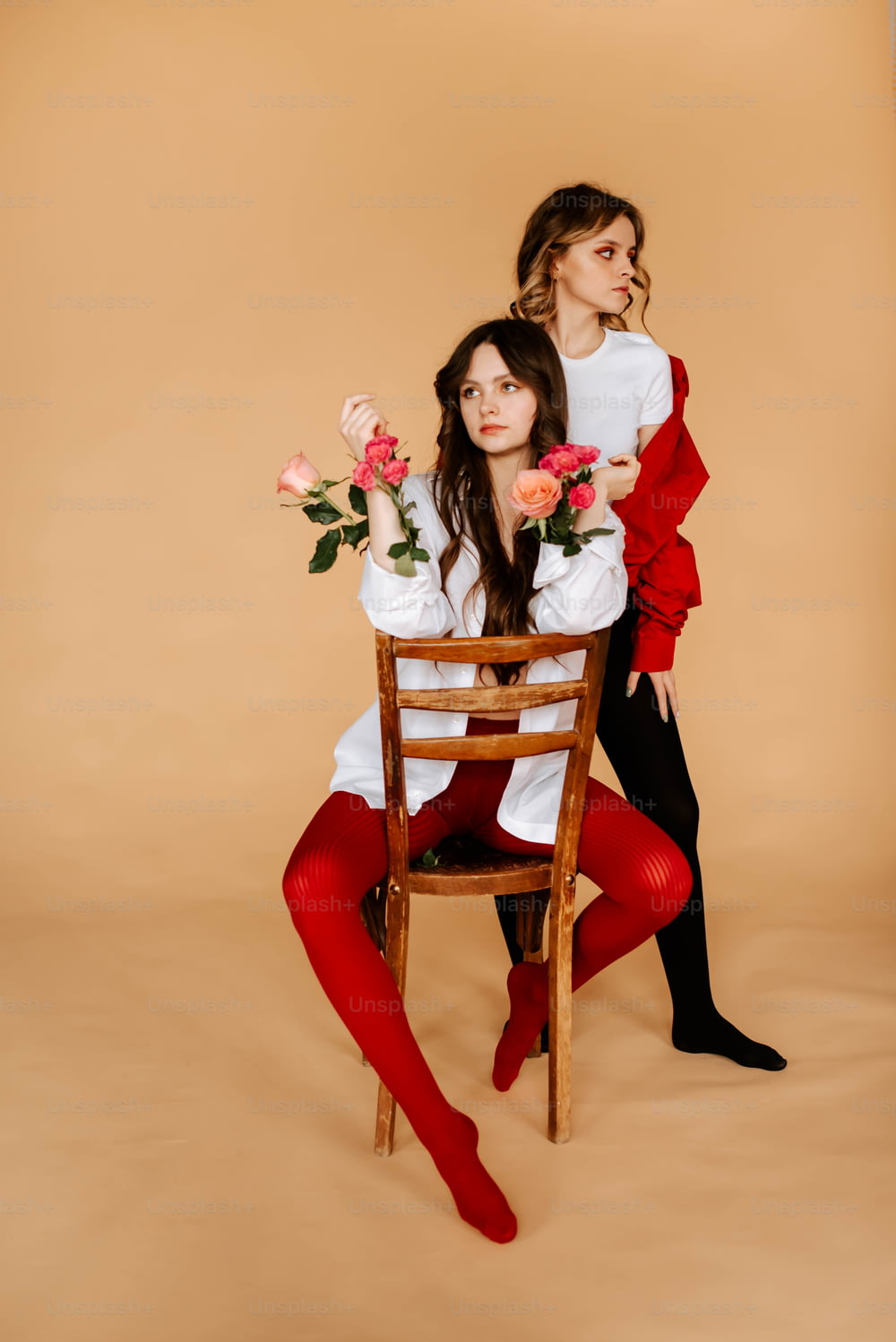 two women sitting on a chair with flowers in their hands