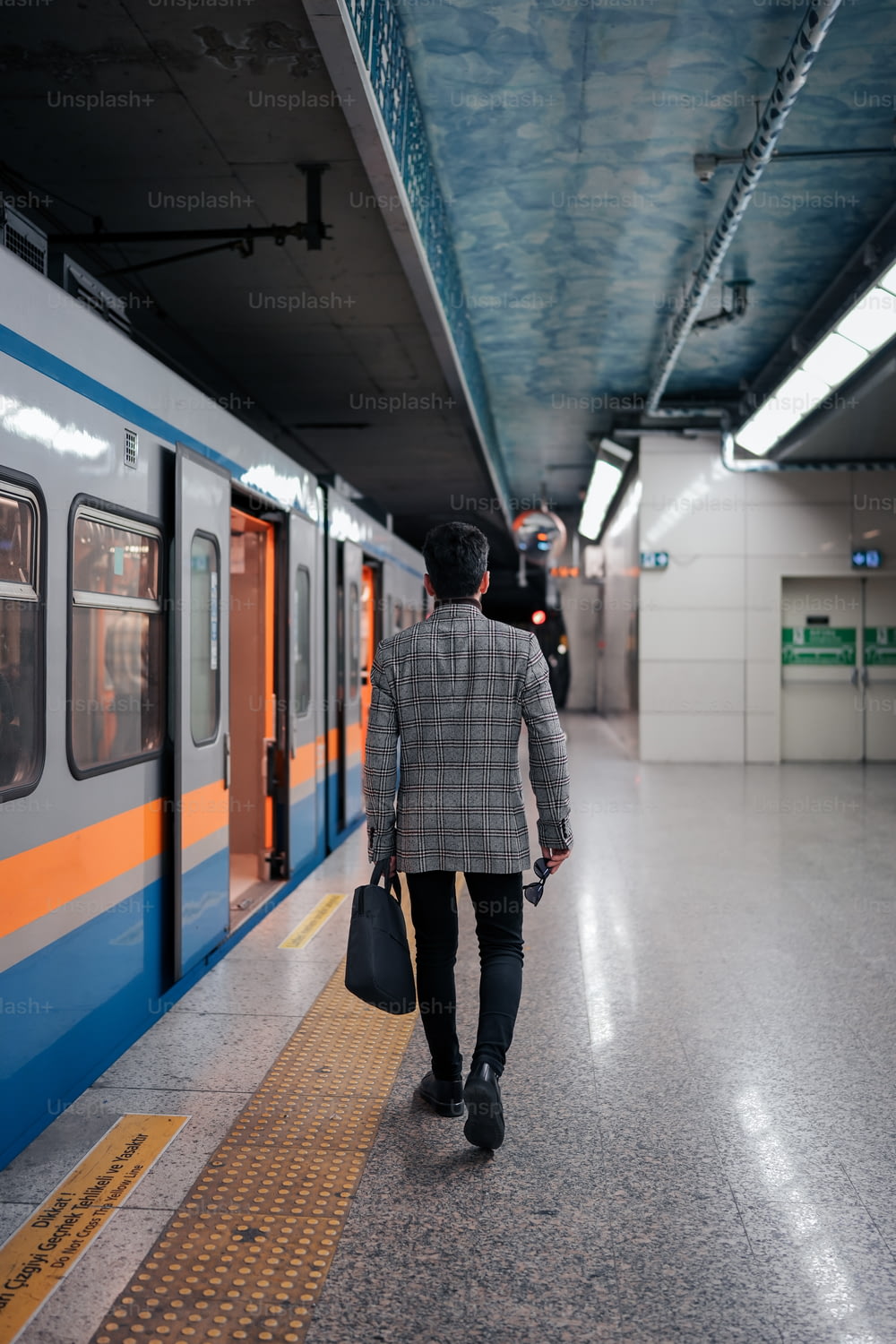 a man walking down a subway platform carrying a bag