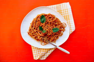un piatto di spaghetti con basilico in cima