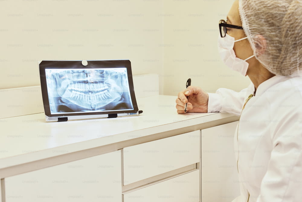 a woman in a white lab coat writing in front of an x - ray