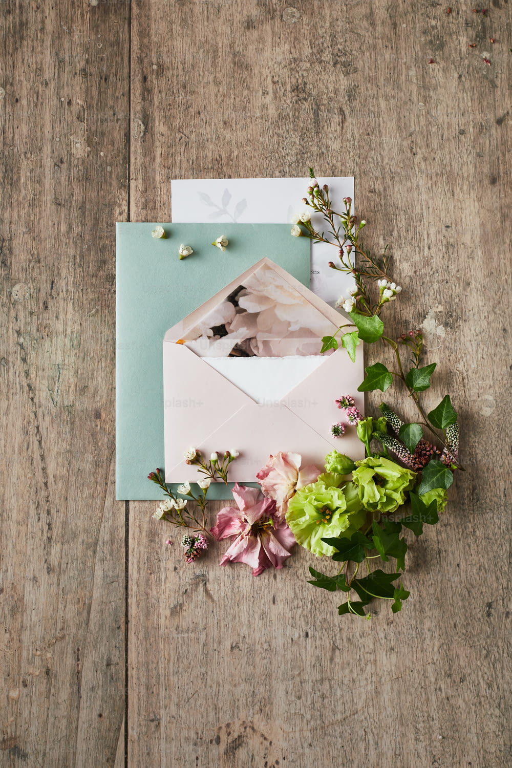 a pink envelope with flowers on a wooden table