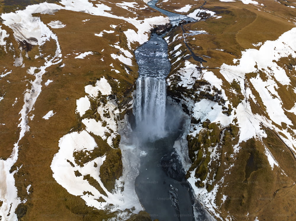 an aerial view of a waterfall surrounded by snow