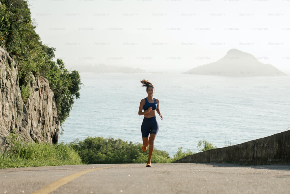 uma mulher correndo por uma estrada ao lado do oceano