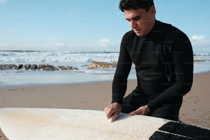 서핑 보드 옆 해변에 앉아있는 남자