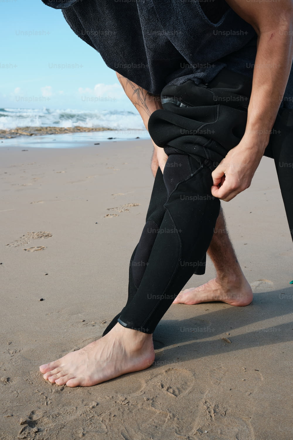 Un uomo in muta è in piedi sulla spiaggia