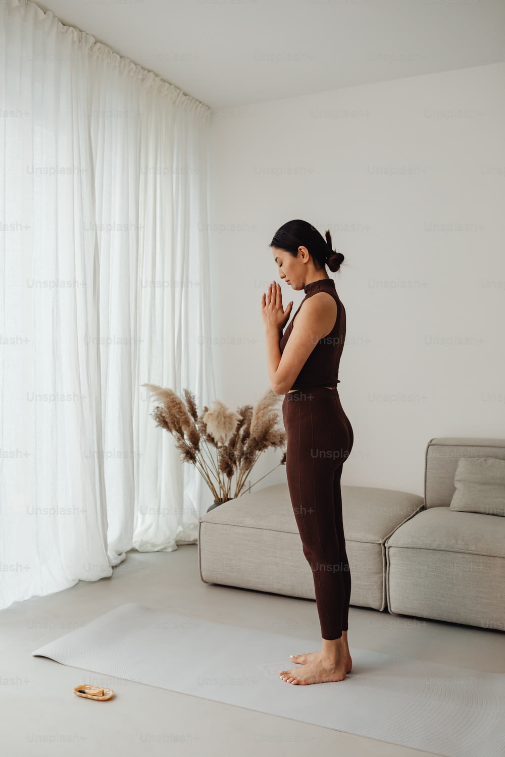 Una mujer parada en una esterilla de yoga frente a un sofá