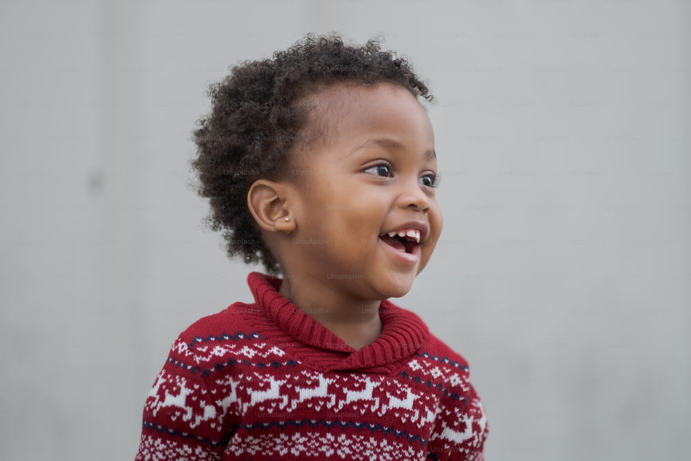 Un bambino sorride mentre indossa un maglione rosso