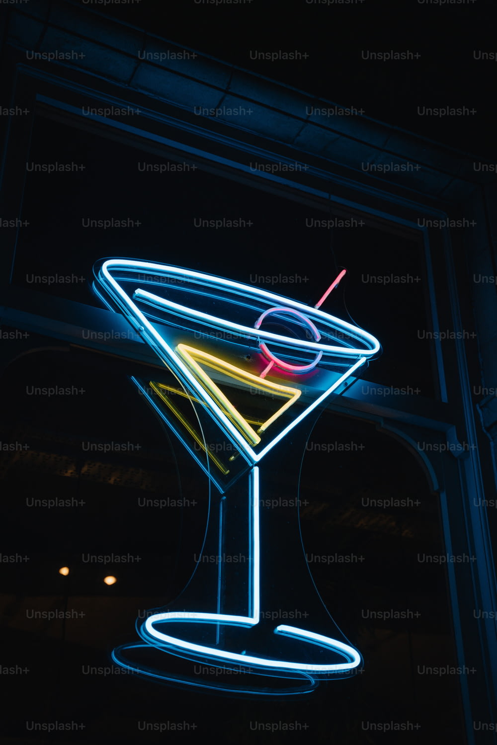 un verre à martini éclairé avec une paille dedans