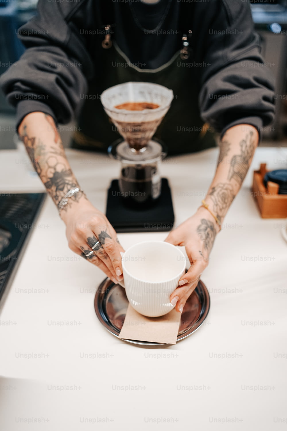 um homem com tatuagens em seus braços segurando uma xícara de café