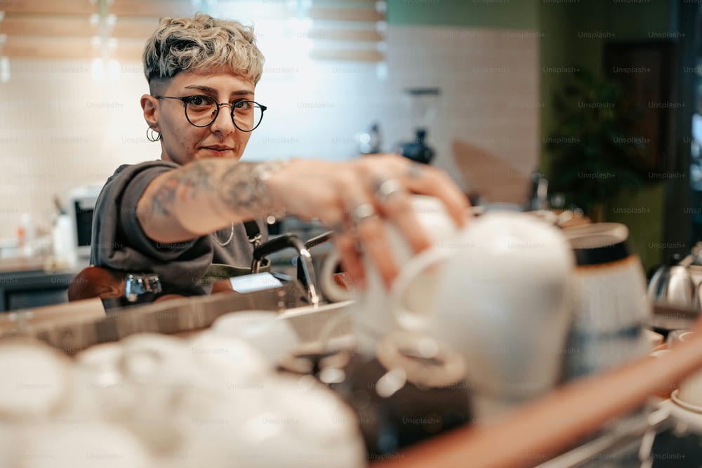 a woman in glasses is pouring a cup of coffee