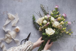 a person holding a bouquet of flowers next to a pair of scissors
