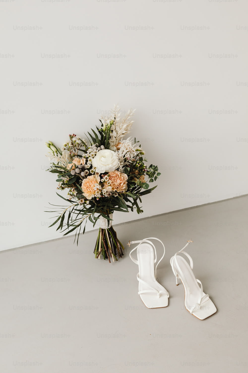 um buquê de flores e um par de sapatos brancos