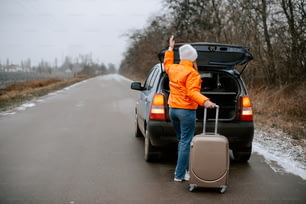 a woman in an orange jacket is holding a suitcase