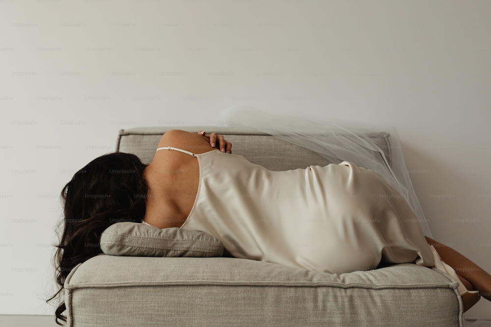 a woman in a white dress laying on a couch
