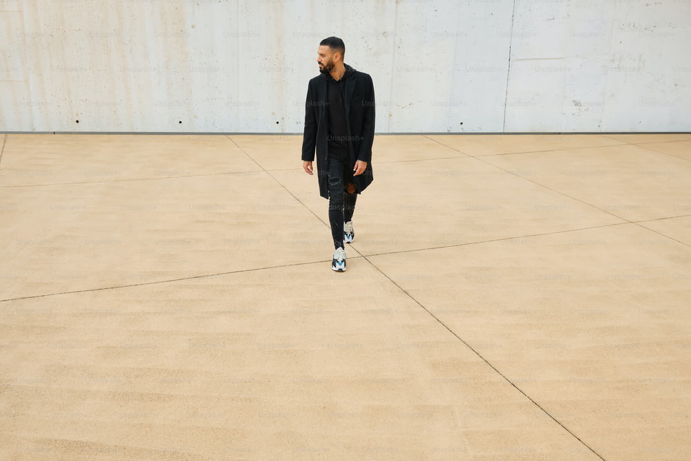 Un uomo in un abito nero che cammina su un pavimento di cemento